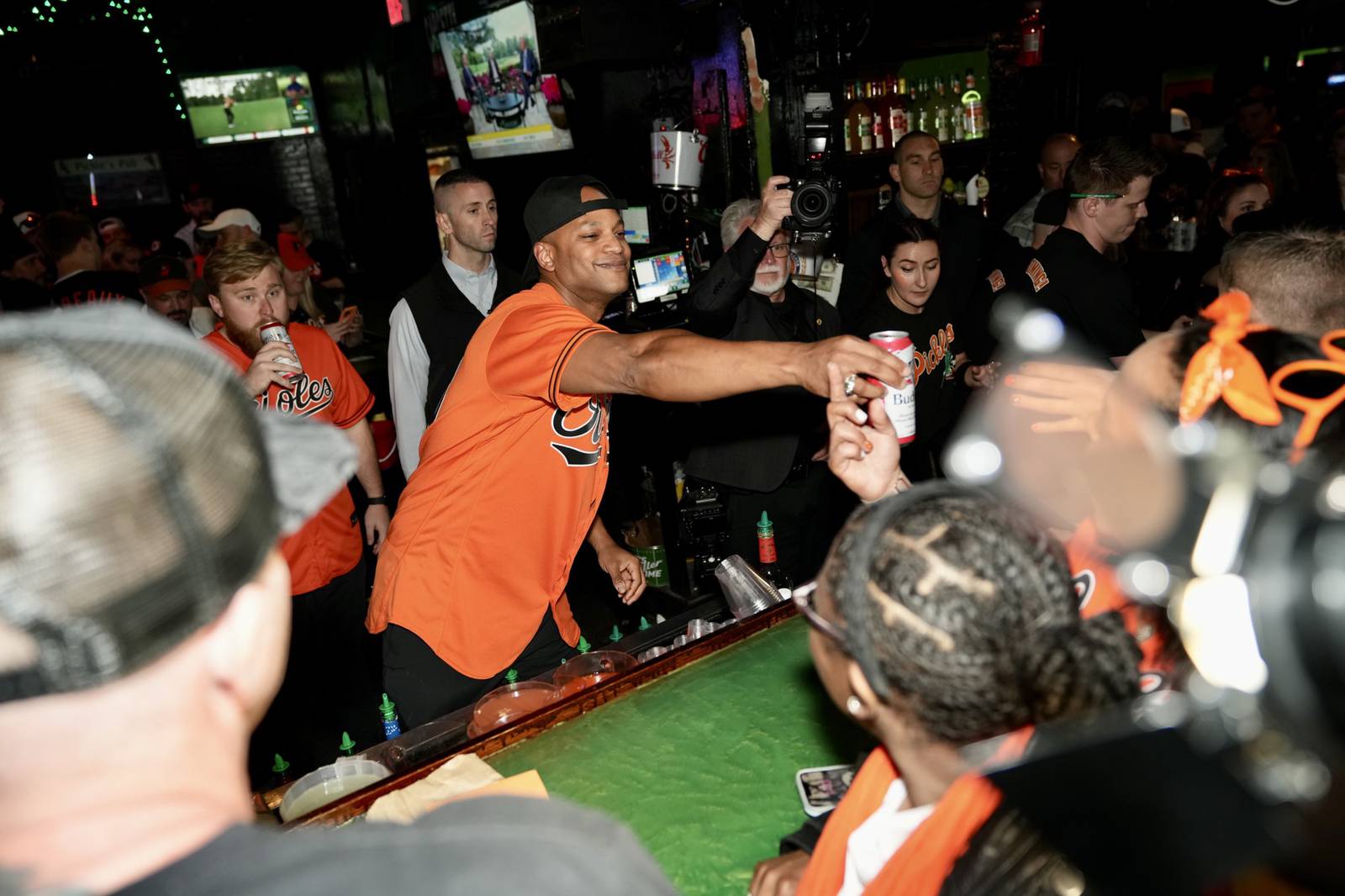 Gov. Wes Moore hands out beer and handshakes from behind the bar at Pickles Pub to excited O’s fan, on April 7, 2023.