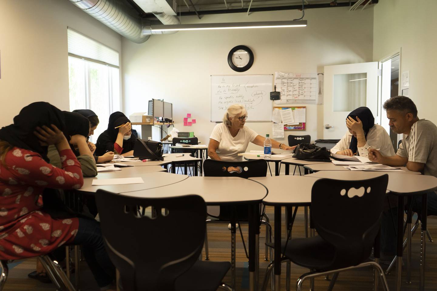 Judy Frye Jones, a volunteer English teacher at the St. Francis Neighborhood Center, has her Afghan students read aloud from lesson packets. The students work together to understand confusing words and deciding if the sentences are correct.