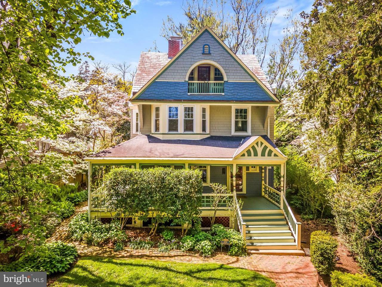 A shingle style cottage home in Roland Park with lots of trees and greenery around it.