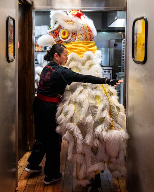 Winnie Lam helps a lion enter the kitchen of Asian Court in Ellicott City, Md. on Sunday, Feb. 18, 2024. By entering the kitchen of a restaurant, the lion is blessing the business for the year.