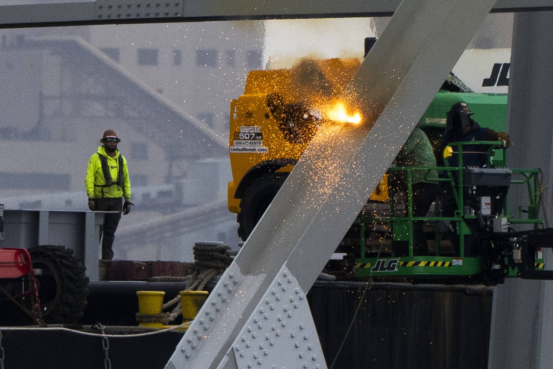 Workers are seen in the beginning stages of dismantling the steel from the frame of the collapsed Key Bridge on April 4, 2024. They are using an exothermic cutting torch.