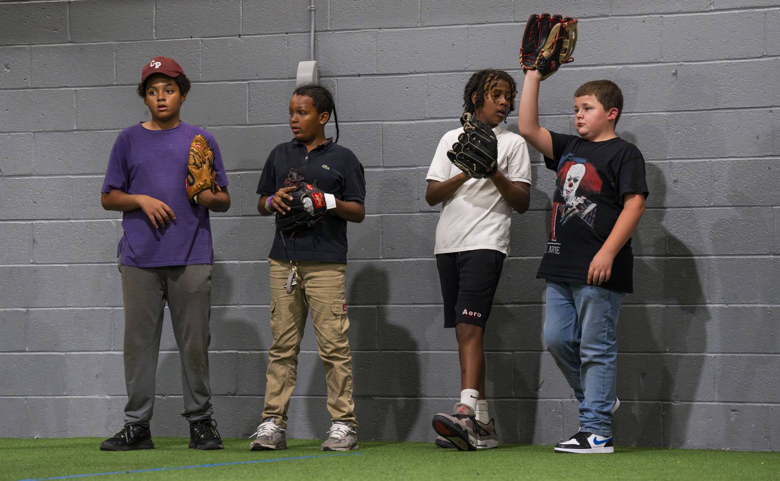 Children line up against the wall to practice catching on October 4, 2023 at the Baltimore Urban Baseball Academy, BUBA, in South Baltimore.
