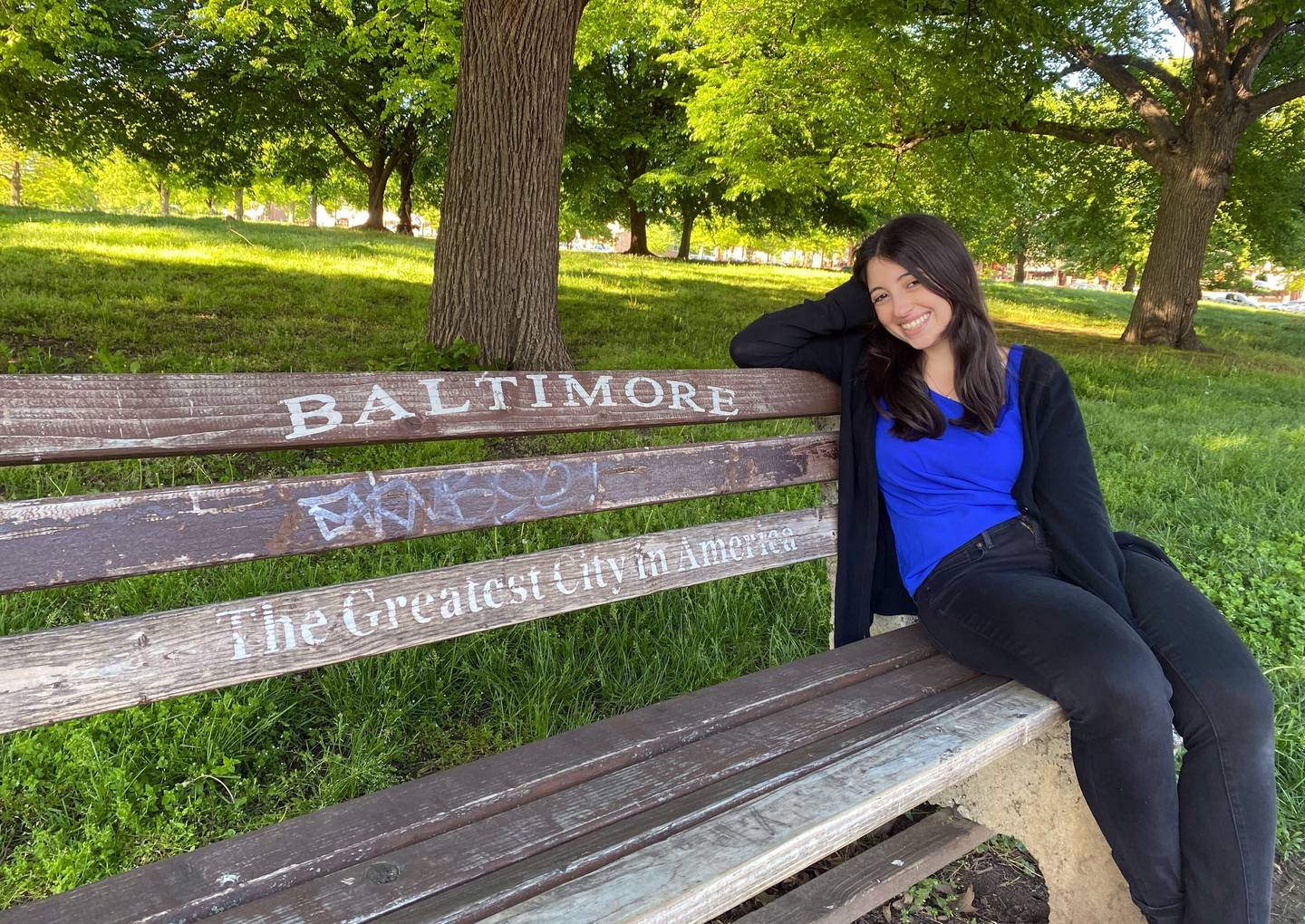 Baltimore Banner reporter Hallie Miller sits in Patterson Park on one of the iconic Baltimore, "The Greatest City in America" benches. Photo by Joanna Kozlowski DuBose