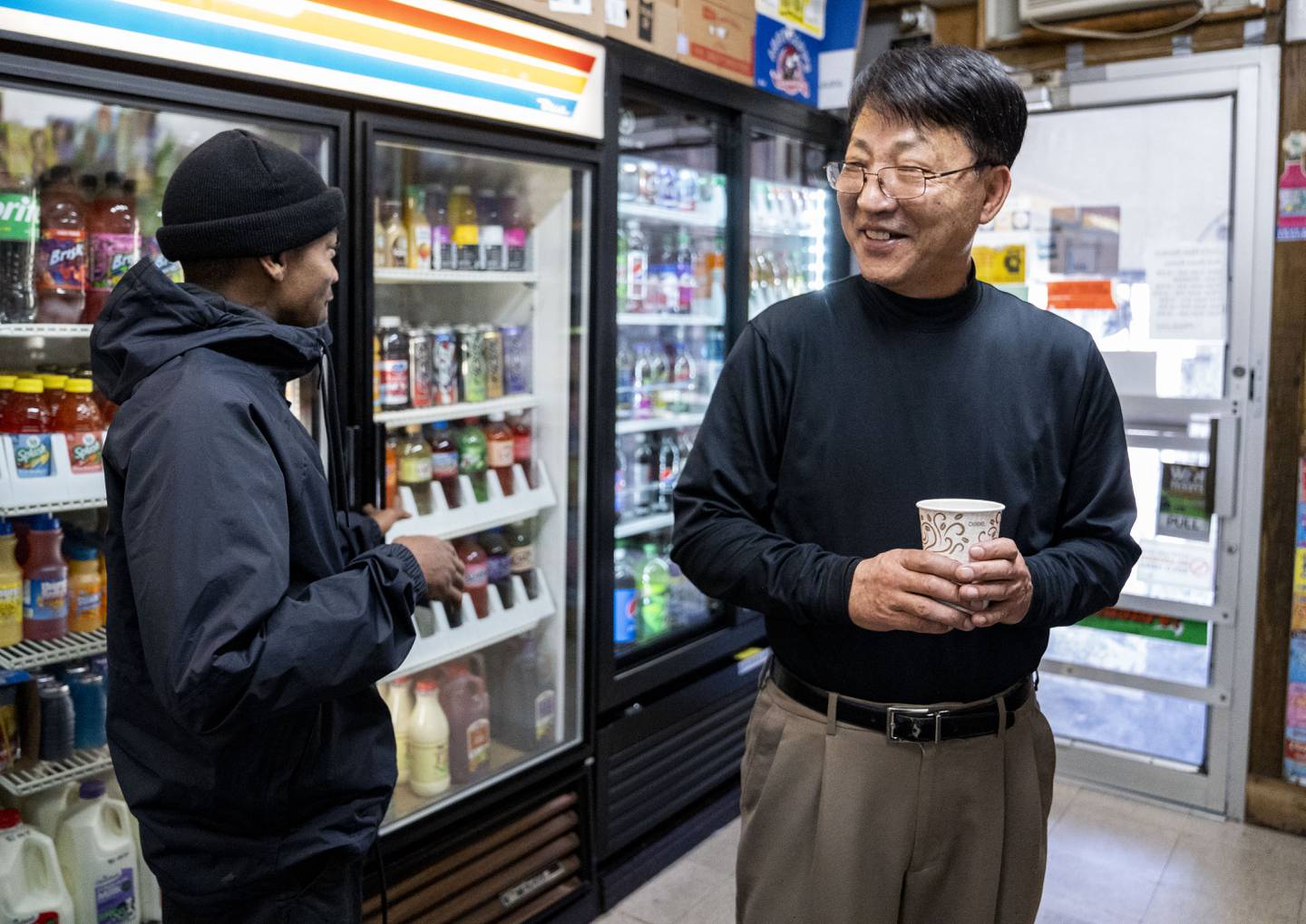 Kevin Lee talks with Anthony Austin, a customer who has been visiting the corner store for year, at Lee's Mini Market, in Baltimore, Thursday, December 1, 2022.