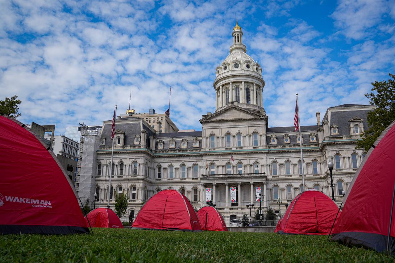 Red tents occupy the lawn at the homeless encampment outside City Hall on August 17, 2022. The Black Community Development Coalition and homeless advocates set up an encampment Wednesday at the War Memorial Plaza to encourage Baltimore leaders to make the encampments around the city more of a priority.