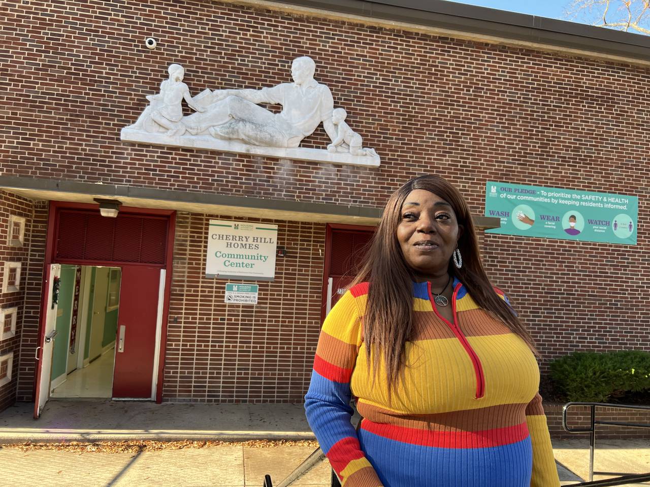 A woman in a striped dress stands in front of a community center.
