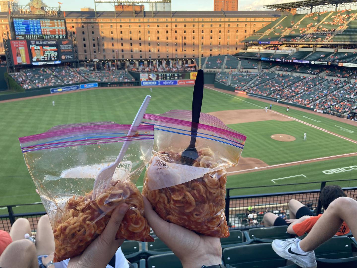 Two bags of pasta in a red marinara sauce held aloft from the stands of Camden Yards.
