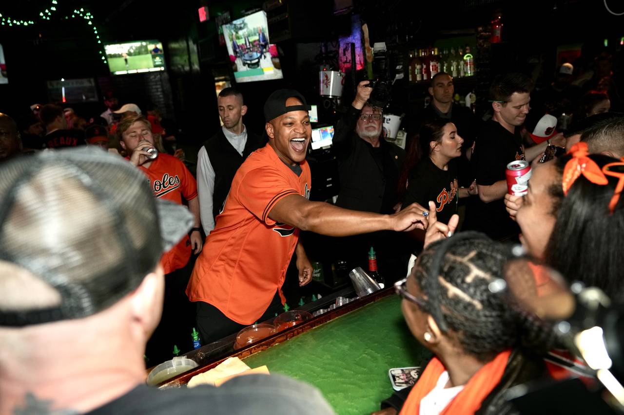 Governor Wes Moore hands out beer and handshakes from behind the bar at Pickles Pub to excited O’s fan, on April 7, 2023.