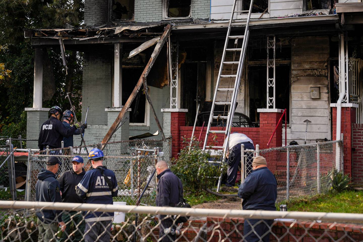 Baltimore City Fire Department and ATF officials examine multiple burned rowhomes in the 5200 block of Linden Heights Ave. on Friday, October 20, 2023. The fatal fire the previous night took the lives of two firefighters and injured multiple others.