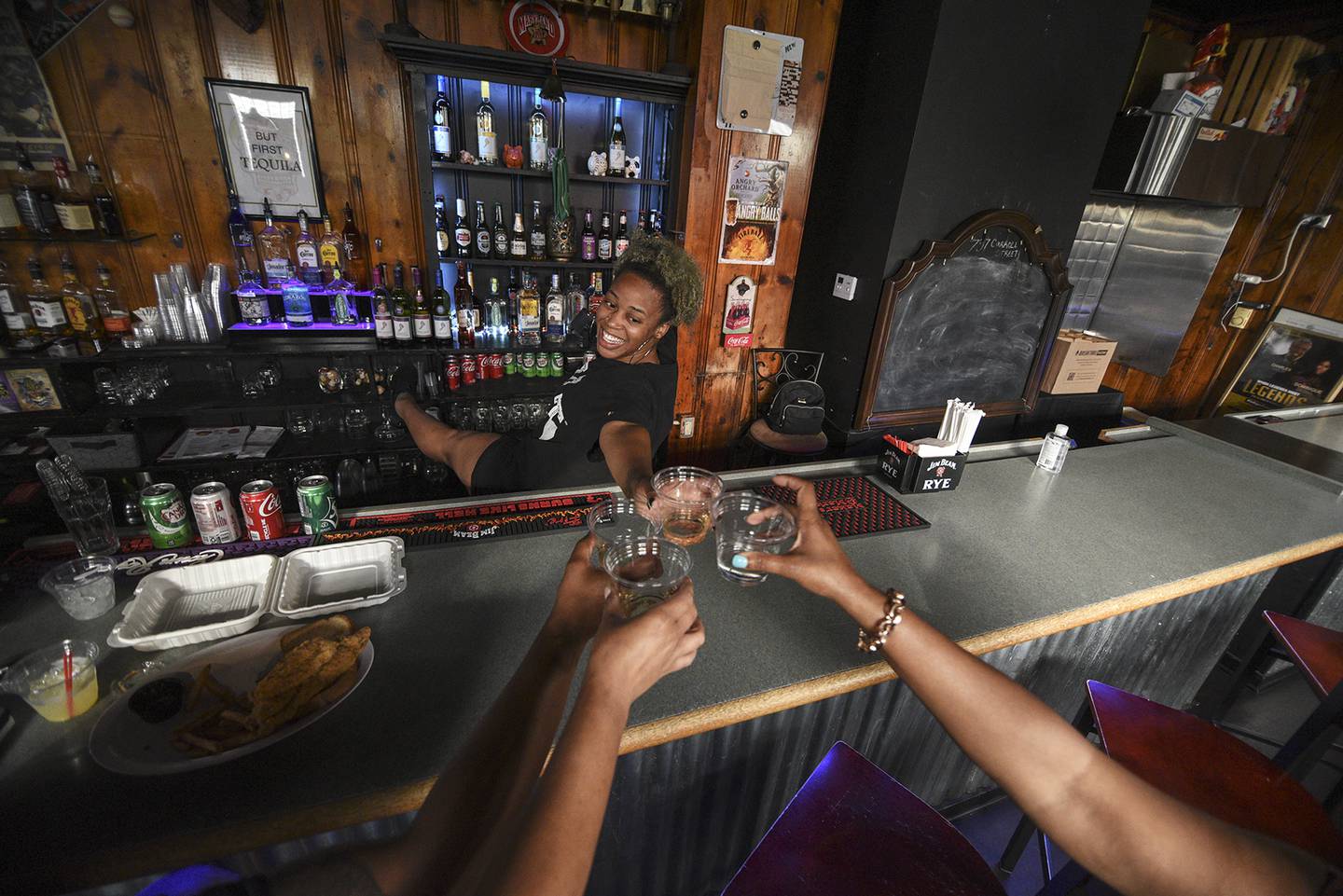 Head bartender Nikki Robinson toasts with regulars at Friends Grille in Pigtown