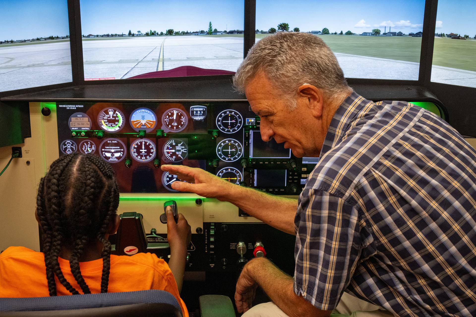 Instructor Jerry Hinshaw teaches a camper how to take off from the runway during a flight simulation.