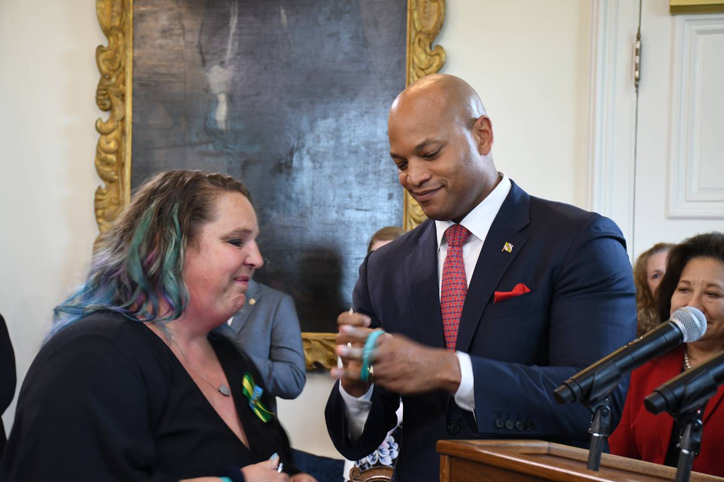 Melissa Willey, the mother of the late Jaelynn Willey, gives a commemorative bracelet to Gov. Wes Moore at a bill signing ceremony at the State House in Annapolis on Tuesday, May 16, 2023. Jaelynn was fatally shot at school by a classmate in 2018, and a new law named for her tightens the law for keeping guns away from minors.