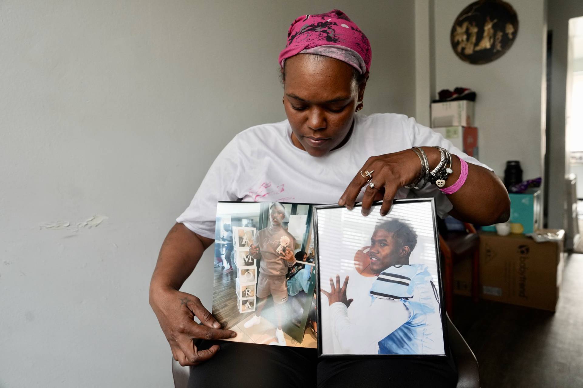 Shantera Ebanks, mother of K’Mauri Ebanks, holds up photos of him in her home on June 6, 2023. She still wears the pink “trauma” hospital bracelet from when he was admitted to Shock Trauma.