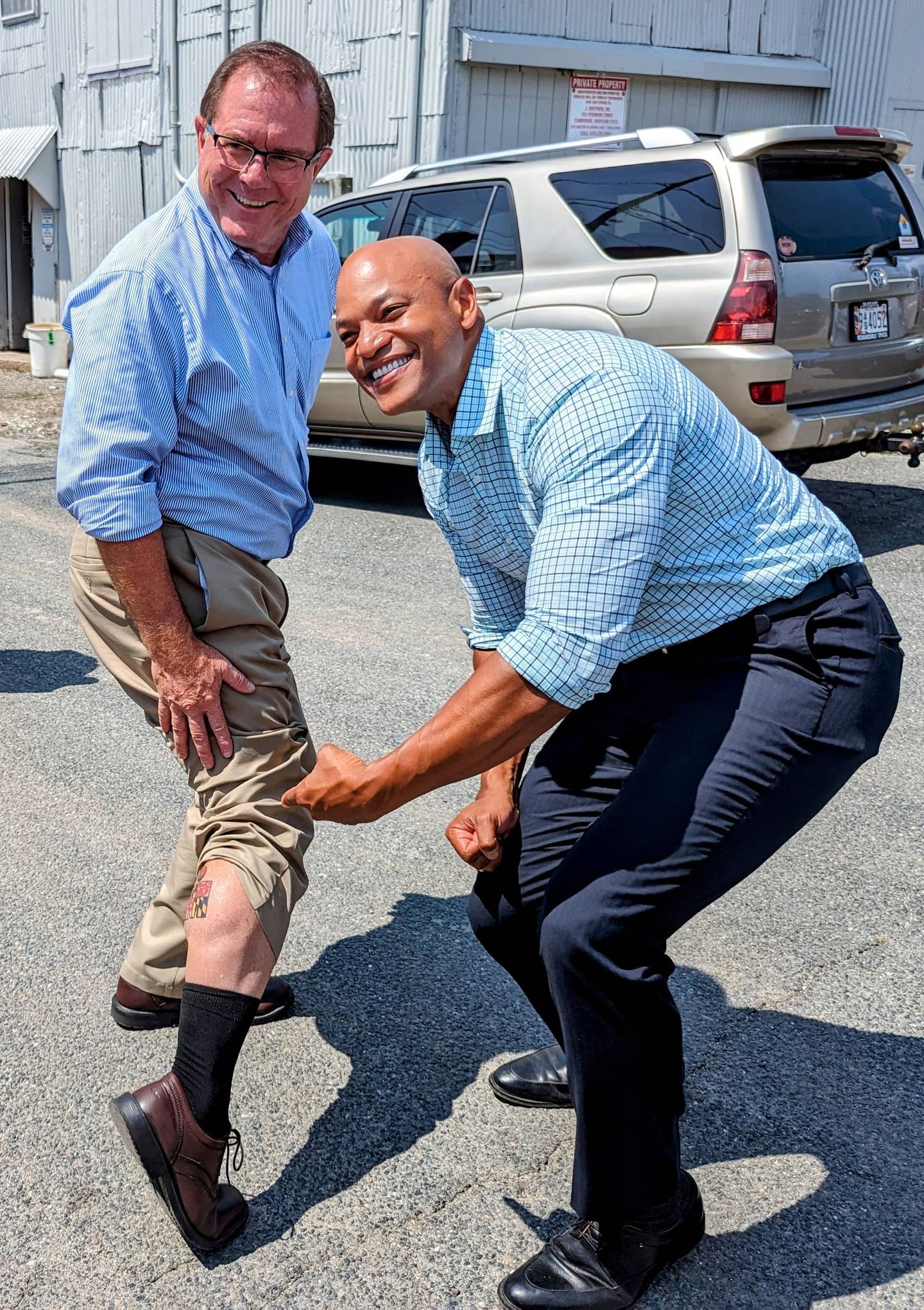Gov. Wes Moore, left, poses for a photo with state Del. Tom Hutchinson after the Republican from Cambridge showed off the tattoo he got to celebrate completing a local Ironman competition. The governor was visiting a seafood processing plant in Cambridge on Thursday, July 20, 2023.