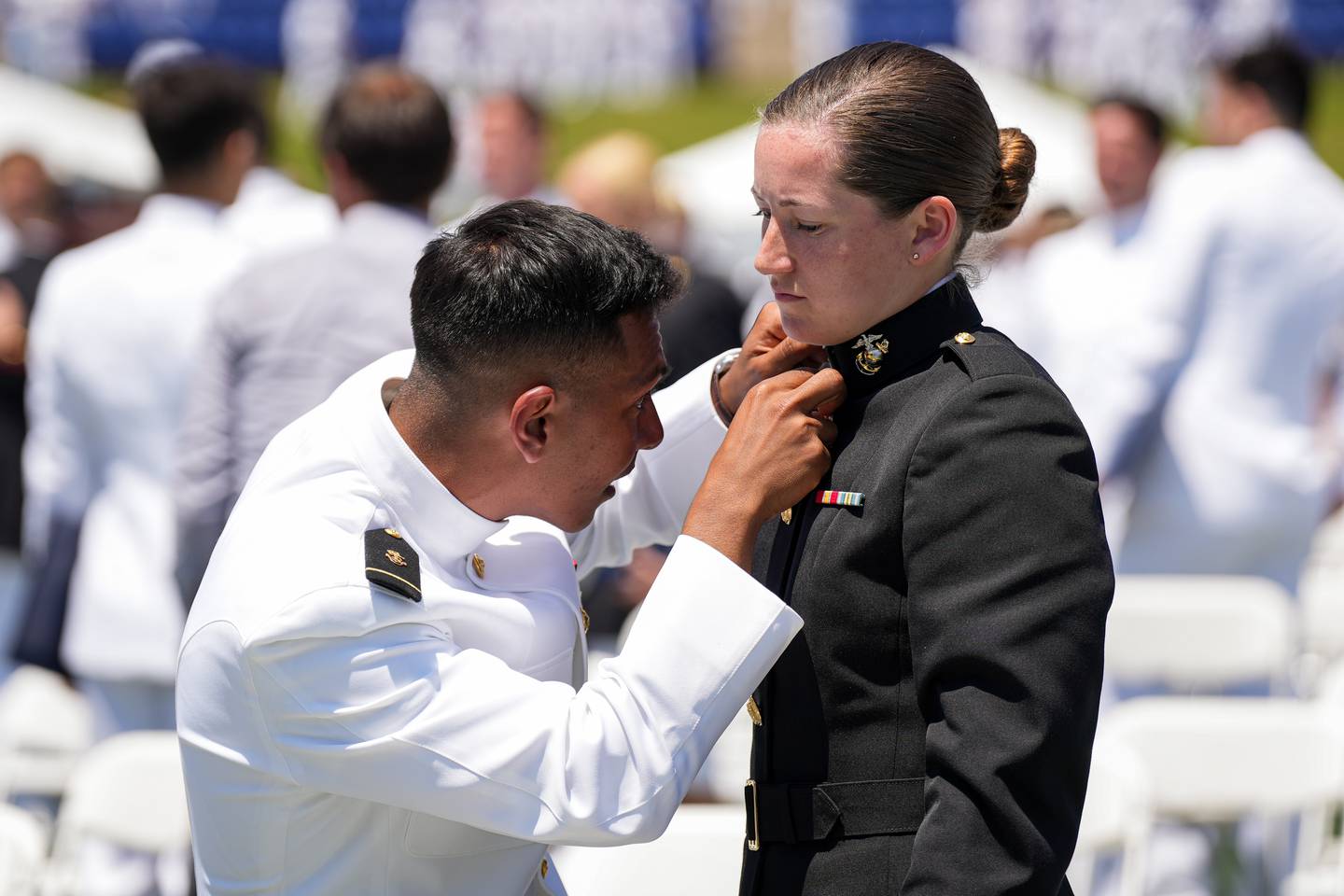 One just-graduated ensign helps adjust the collar of a newly commissioned second lieutenant at the conclusion of the U.S. Naval Academy’s graduation ceremony at the Navy-Marine Corps Memorial Stadium on May 26, 2023. The graduating midshipmen are commissioned as either an ensign in the U.S. Navy or a 2nd Lieutenant in the U.S. Marine Corps.