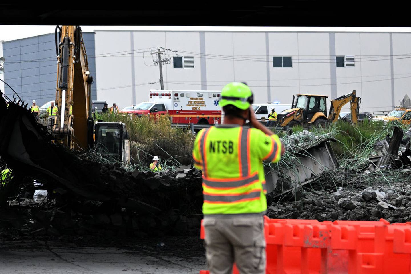 PHILADELPHIA, PENNSYLVANIA - JUNE 12: A person with a National Transportation Safety Board vest photographs a section of bridge that collapsed on Interstate 95 after an oil tanker explosion on June 12, 2023 in Philadelphia, Pennsylvania.  Traffic was severely affected due to the closure of this primary north-to-south highway for East Coast travel.