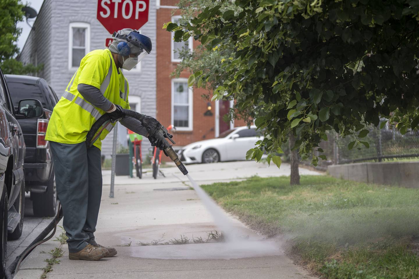Tony Clark, a city graffiti removal worker, uses a wet abrasive blasting machine to erase graffiti on Covington Street.