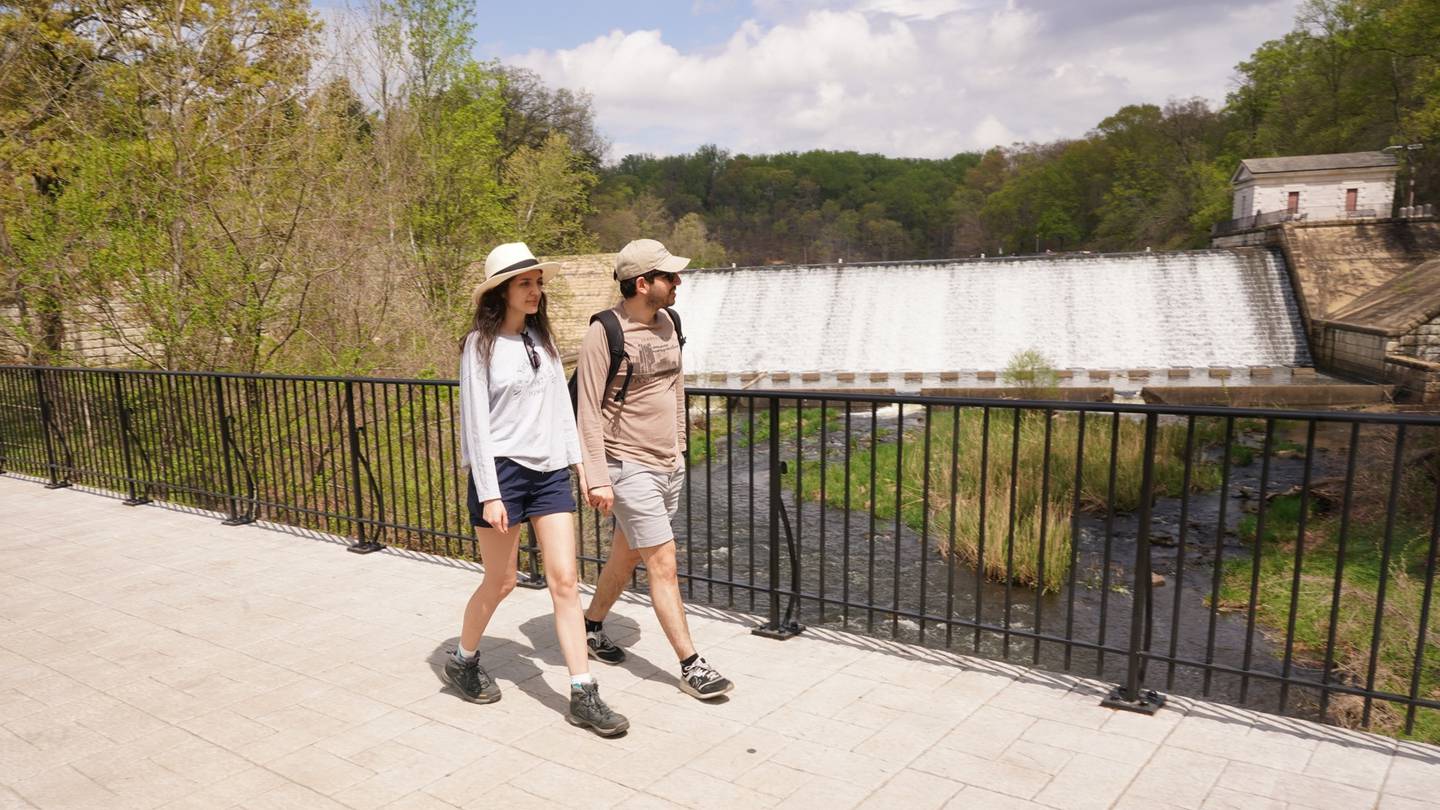 A couple walks across the bridge at Lake Roland Park trails after completing a hike.