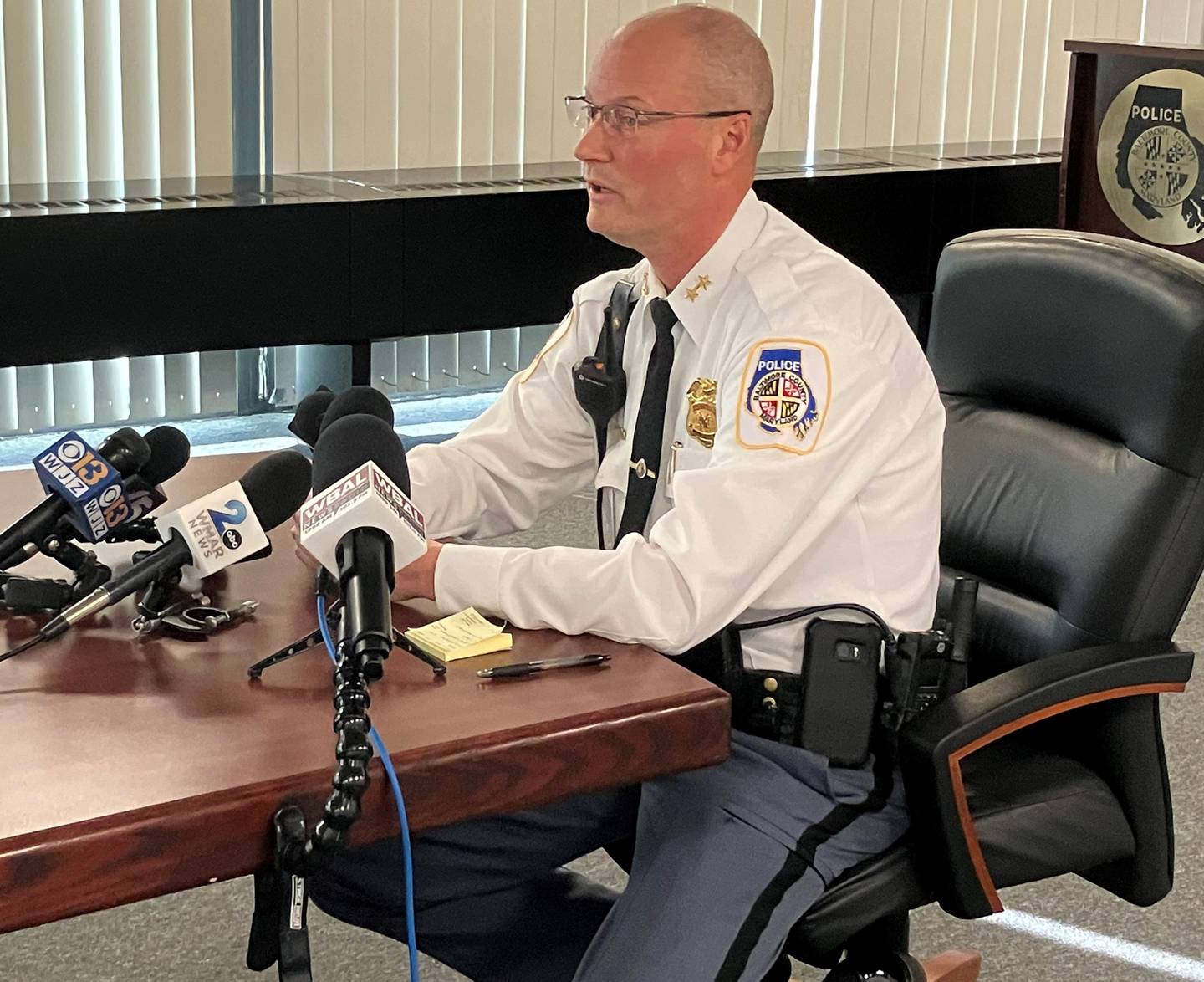 Dennis Delp, interim police chief for Baltimore County, sits at a table. Several microphones are placed on the table and point towards him.