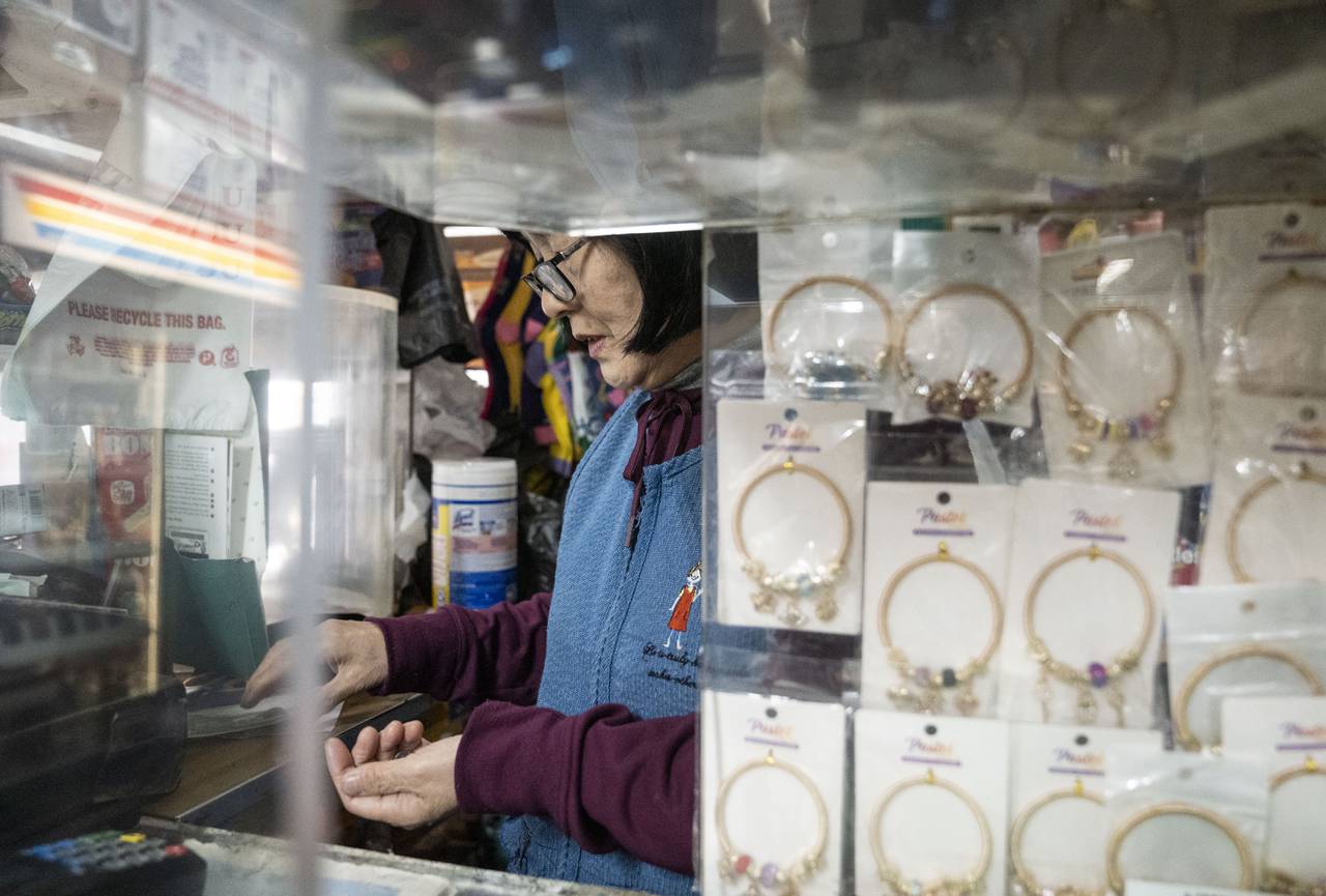 Tae Soon Lee counts change after a customer leaves at Lee's Mini Market, in Baltimore, Thursday, December 1, 2022.