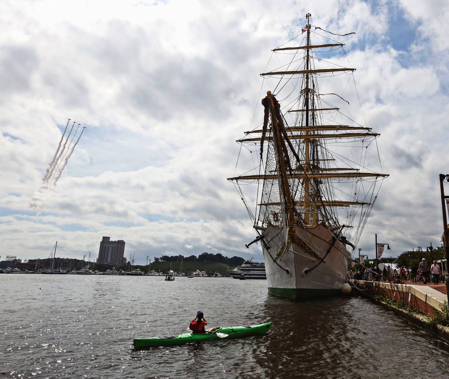 A kayaker takes a photo of the Danmark ship and flight demonstration happening during Baltimore’s FleetWeek at the Inner Harbor.