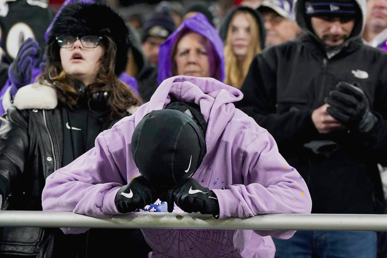 A dejected Ravens fan buries their head in their hands as hope for the Ravens victory starts to slip away.