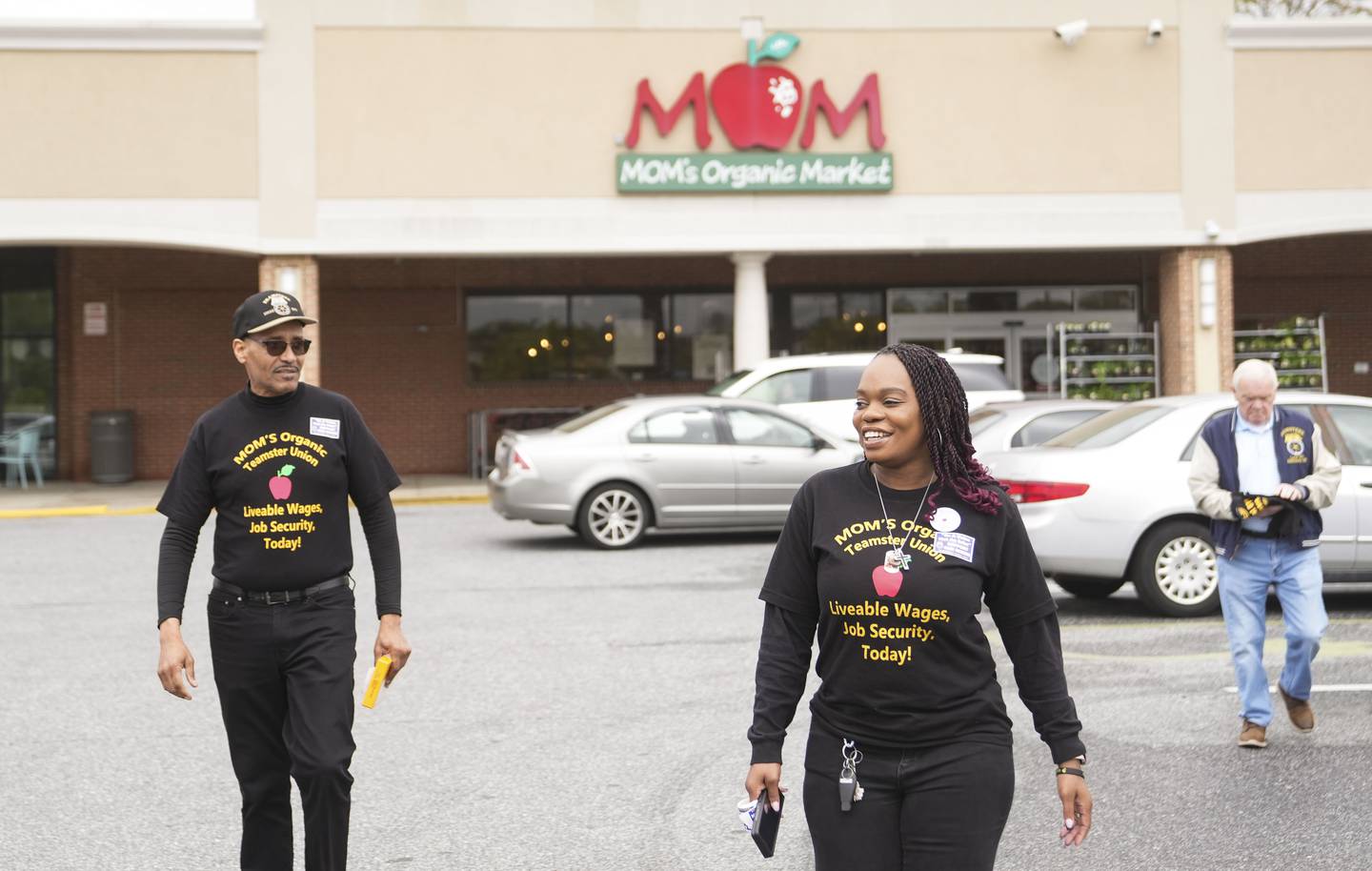 Tia Osborne an organizer for Local 570 and Mo Jackson Vice President of Temasters Local 570 walk outside of MOM’s Organic Market in Timonium, Saturday, April 29, 2023.