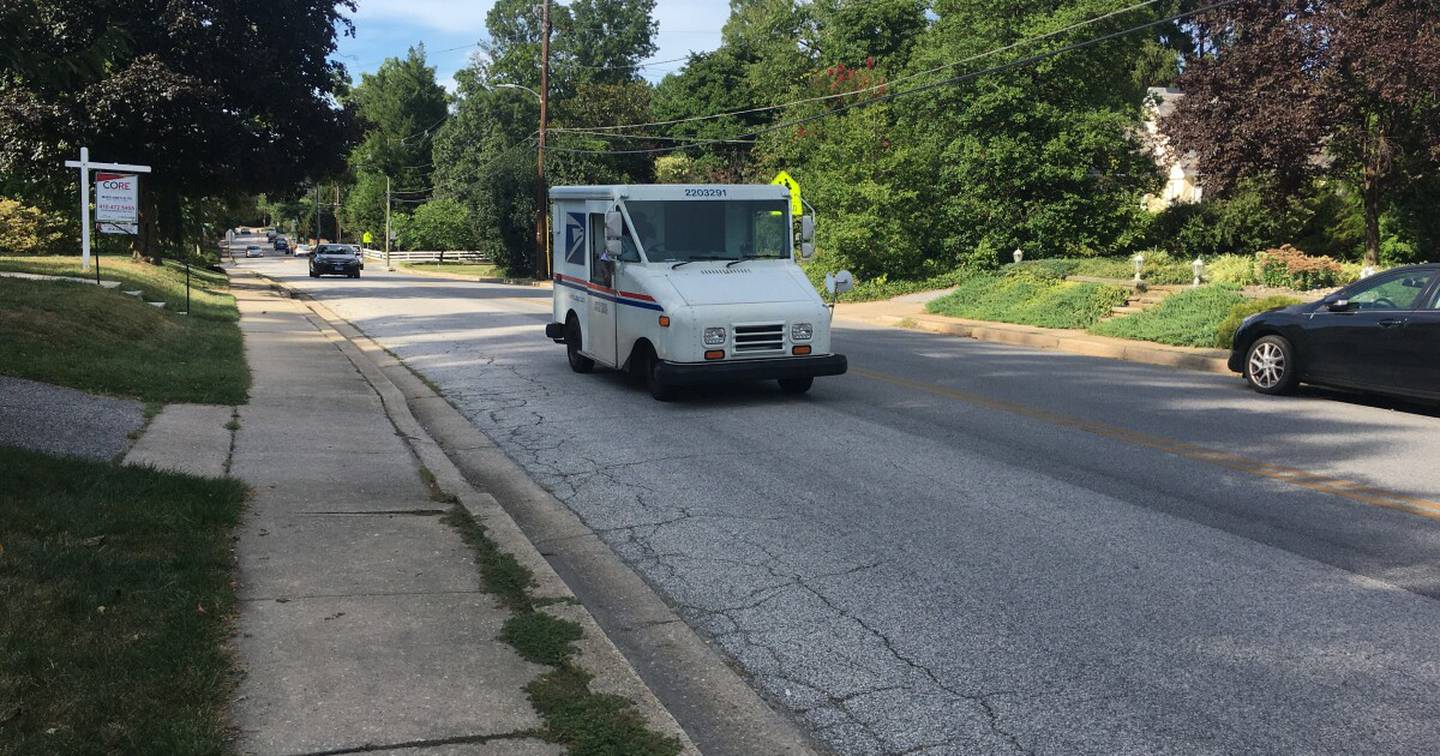 A mail truck drives down Bellona Avenue in Baltimore County. A number of cracks are visible in the road. John Lee/WYPR.