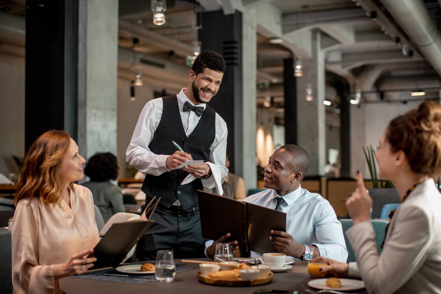 Close up of a waiter taking a order from group of people dining in a restaurant.