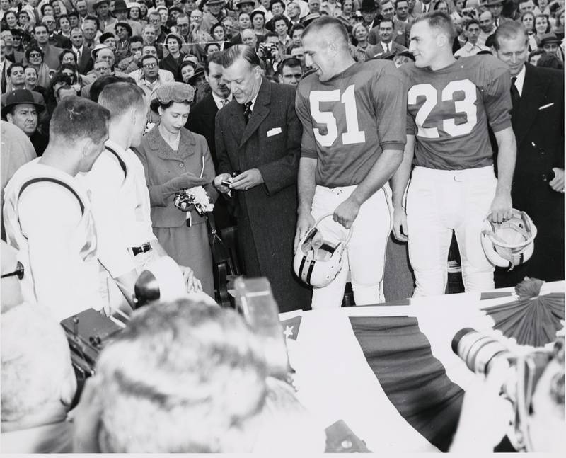 Queen Elizabeth II with Governor Theodore McKeldin and team captains while checking the coin to be used for the coin toss at a University of Maryland football game against the University of North Carolina, October 19, 1957. Prince Philip is pictured at the far right. Courtesy of University of Maryland Archives.