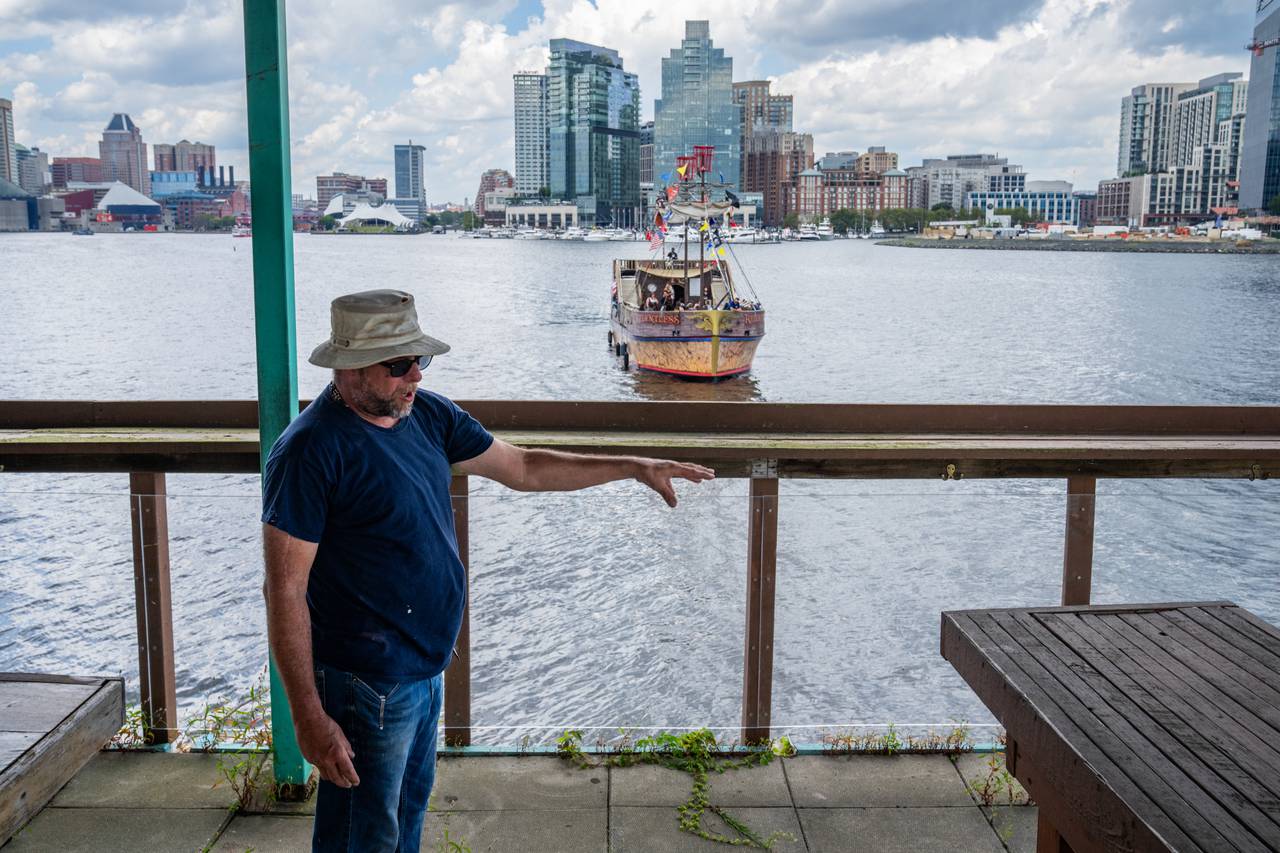 Bernard Dehaene gives a tour of the upper deck of Tiki Barge as a pirate ship sails in the background.