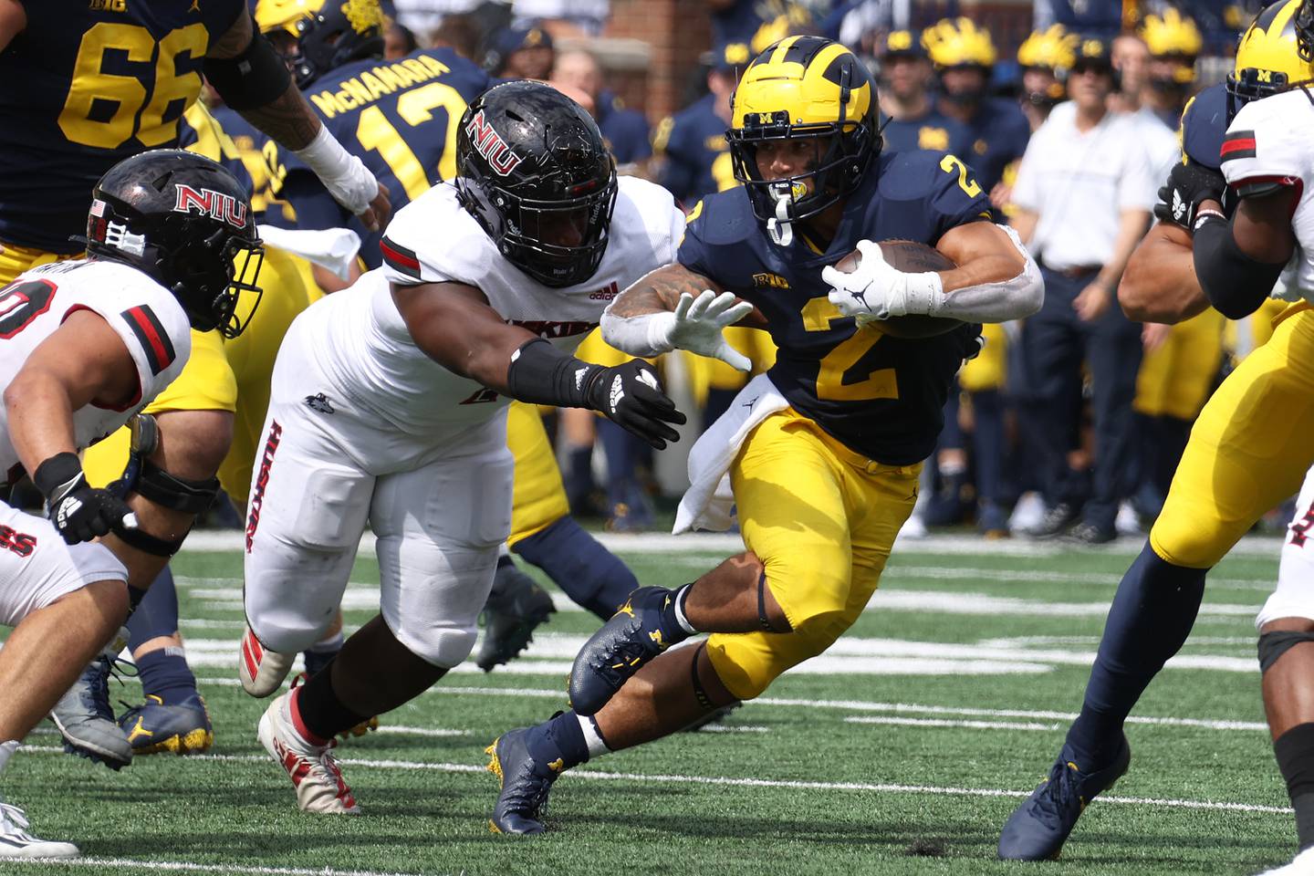 ANN ARBOR, MICHIGAN - SEPTEMBER 18: Blake Corum #2 of the Michigan Wolverines tries to get around the tackle of Nick Rattin #38 and James Ester #1 of the Northern Illinois Huskies during a first half run at Michigan Stadium on September 18, 2021 in Ann Arbor, Michigan.