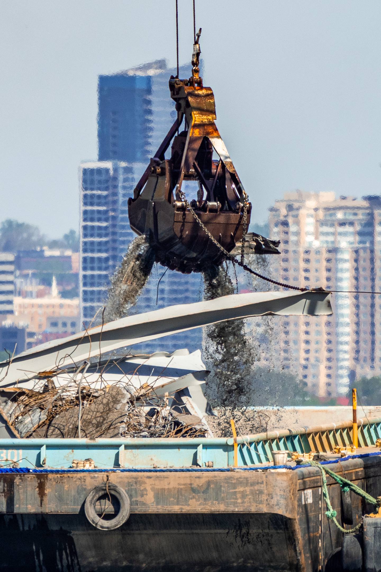A dredge bucket picks up debris from the Patapsco River and deposits it on a barge on Tuesday, April 16, 2024.