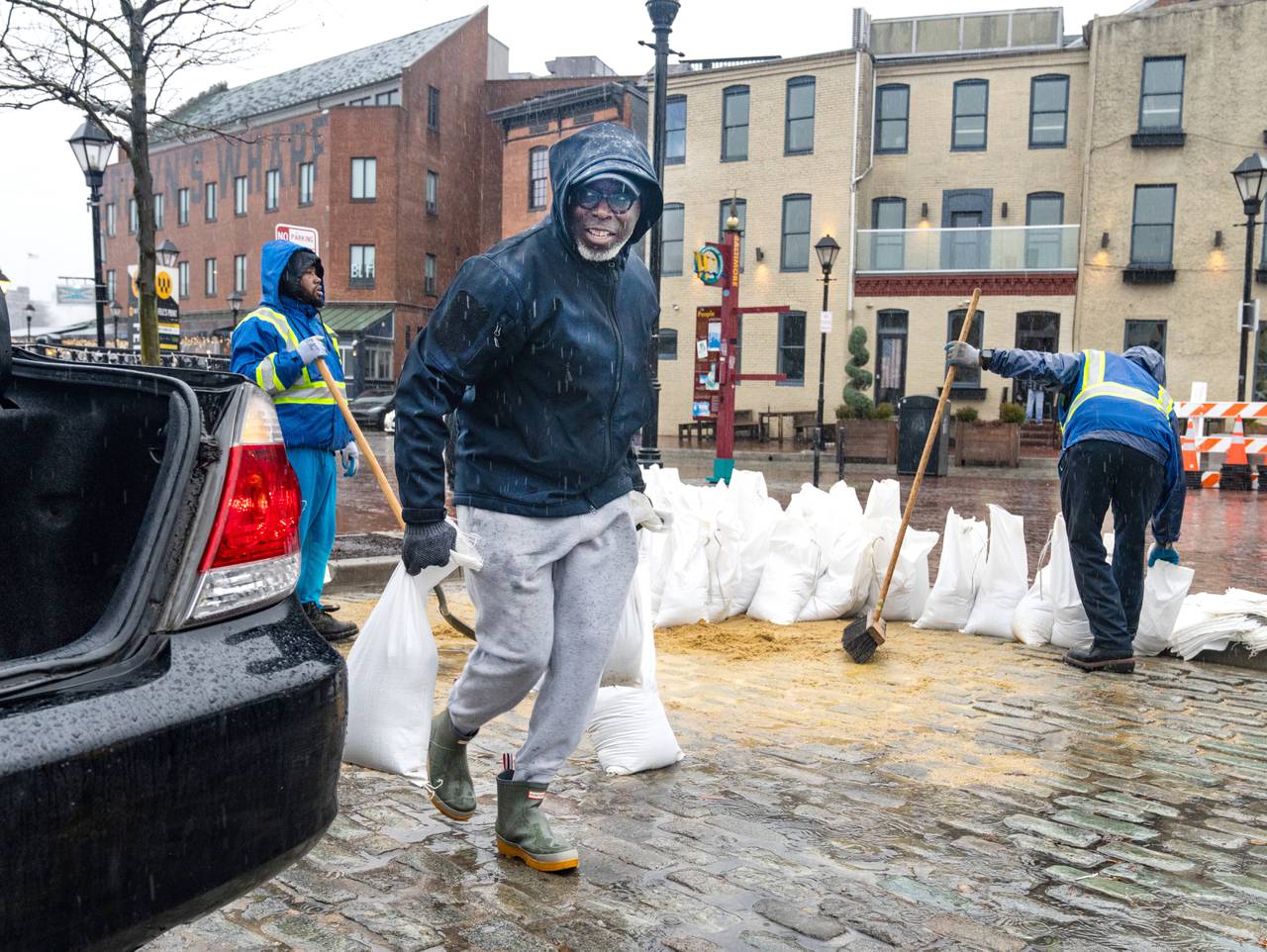 Andre Turner carries sand bags from the City of Baltimore‚Äôs Fells Point pickup location to his car on Tuesday, Jan. 9, 2024. Turner took his lunch break to get the bags because he wanted to make sure he arrived while there were still some left.