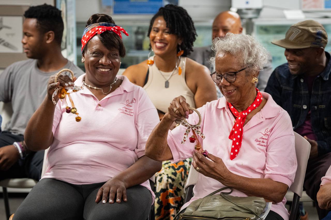 Susan King smiles after ringing bells, a ritual done across the country each Labor Day weekend to honor Rosies. Her daughter, Camille Hinmon, sits beside her, and her grandchildren and great-grandchildren sit behind her.