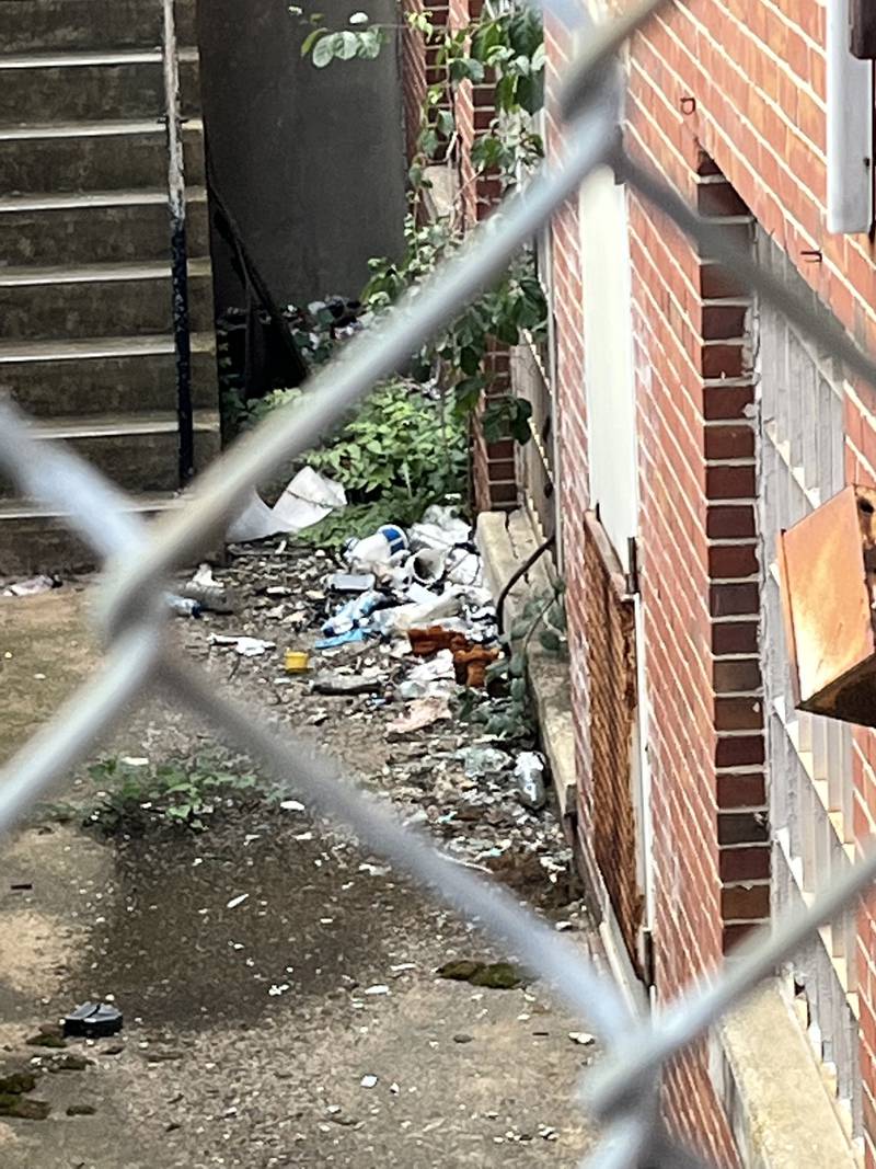 Trash outside the sexual health clinic building at 1515 W North Avenue is seen through a chain-link gate.