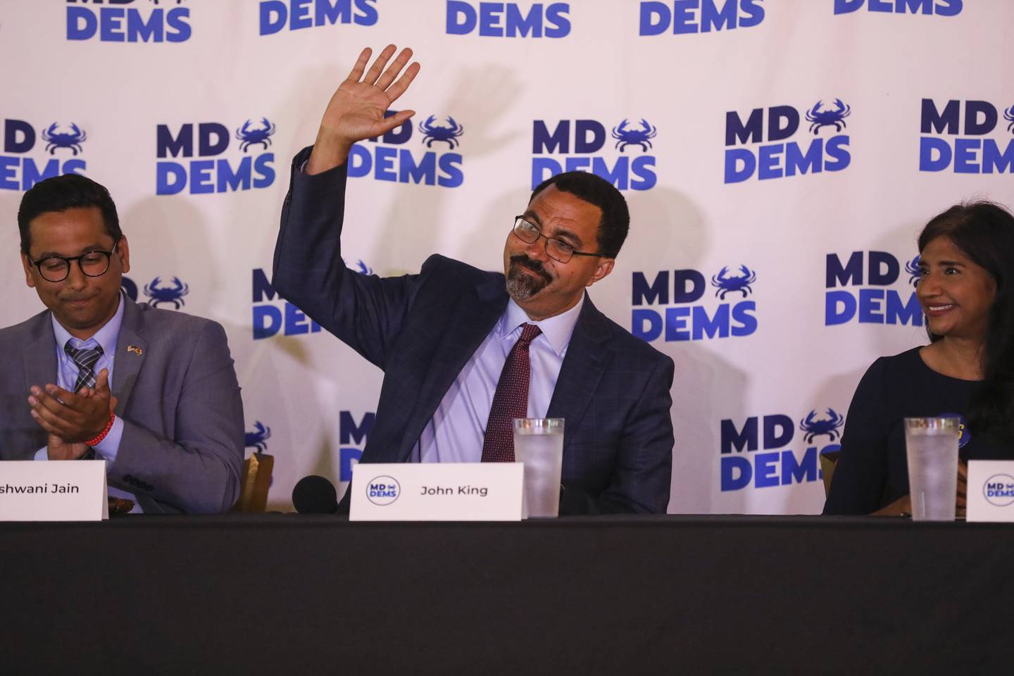 Gubernatorial candidate John King, center, waves to the audience during a forum on healthcare issues sponsored by the Maryland Democratic Party at BC Brewery on May 31, 2022. On the left is gubernatorial candidate Ashwani Jain and to the right is Aruna Miller, the lieutenant governor running mate of Wes Moore, who could not attend because he said he had coronavirus. (Kaitlin Newman for The Baltimore Banner)