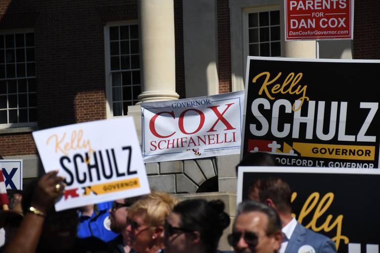 People hold up campaign signs for Republican candidates for governor Dan Cox and Kelly Schulz on Lawyers Mall in Annapolis on June 30, 2022. Schulz called a press conference to denounce "meddling" in the race from the Democratic Governors Association.