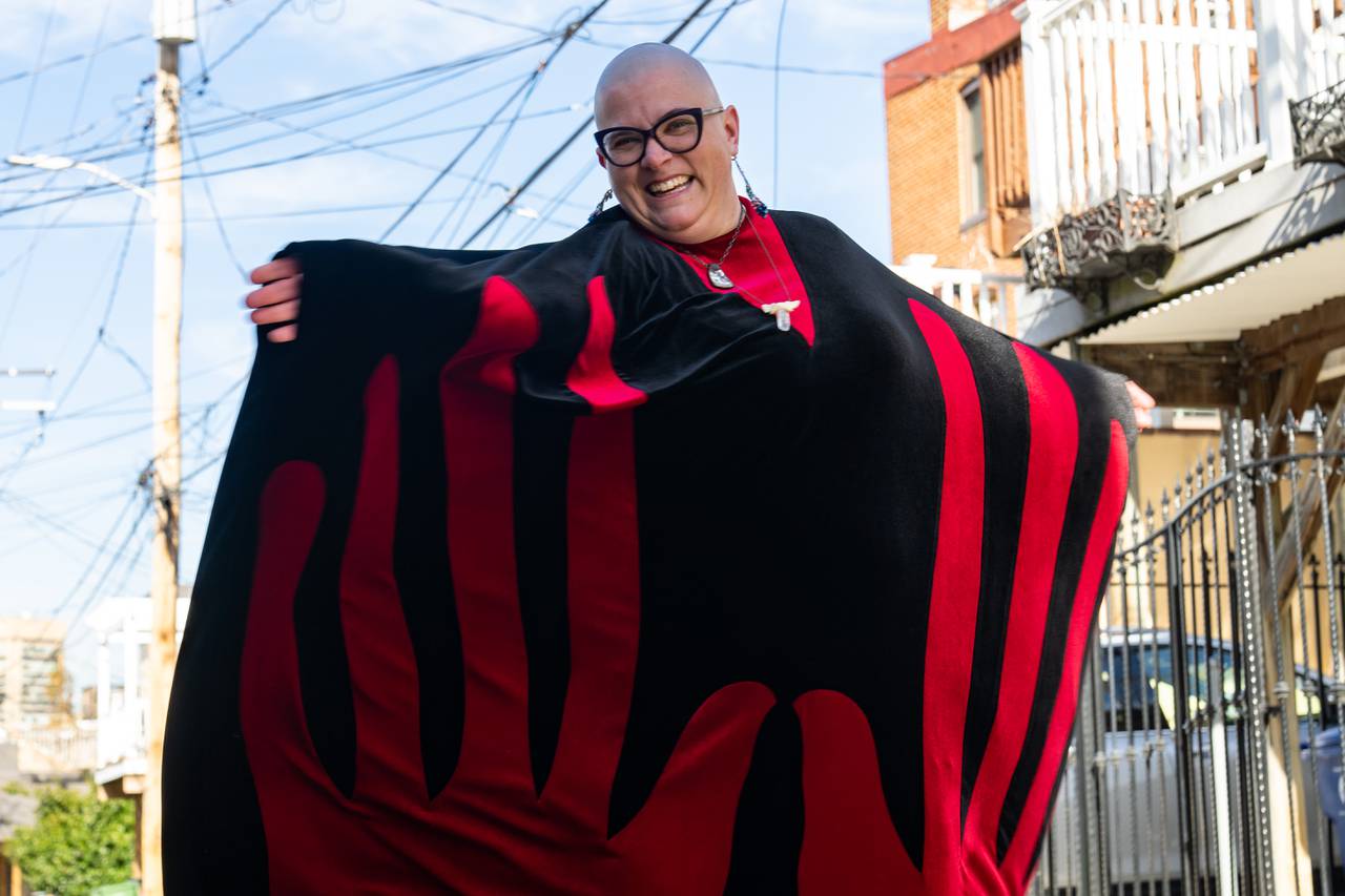Dr. Katie Labor smiles at the camera while twirling in her black and red velvet cloak.