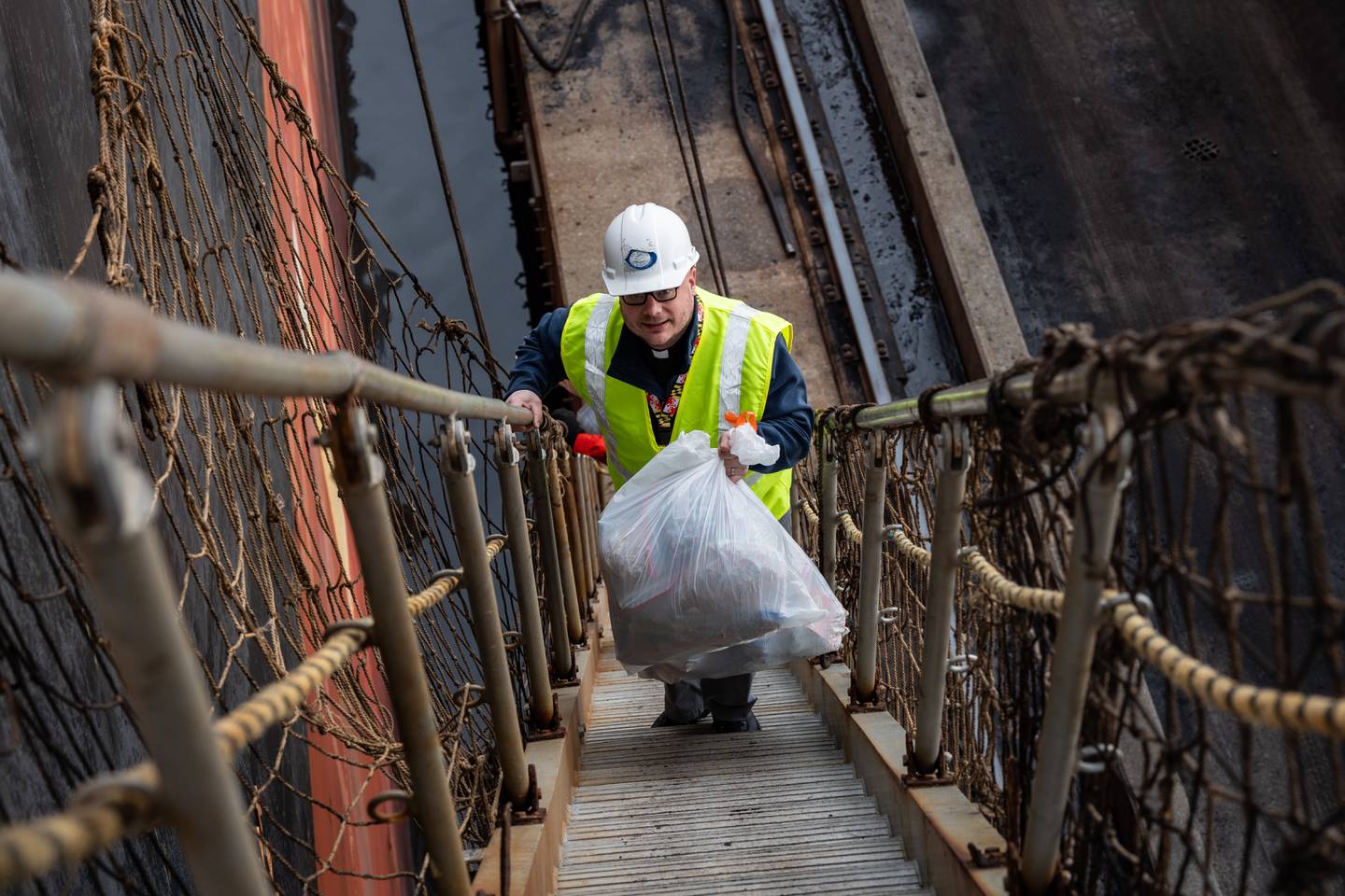 Rev. Joshua Messick walks up the gangway of the Anglo Alexandria holding a white trash bag full of holiday care packages.