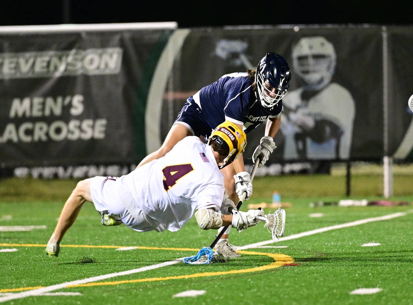 Kent Island defender Henry Gavin (top) thwarts a shot attempt by Hereford's Connor Hartlove as the Buccaneers limited the Bulls to just three goals in winning the 2023 Class 2A Boys Lacrosse state championship, Tuesday night at Stevenson University.