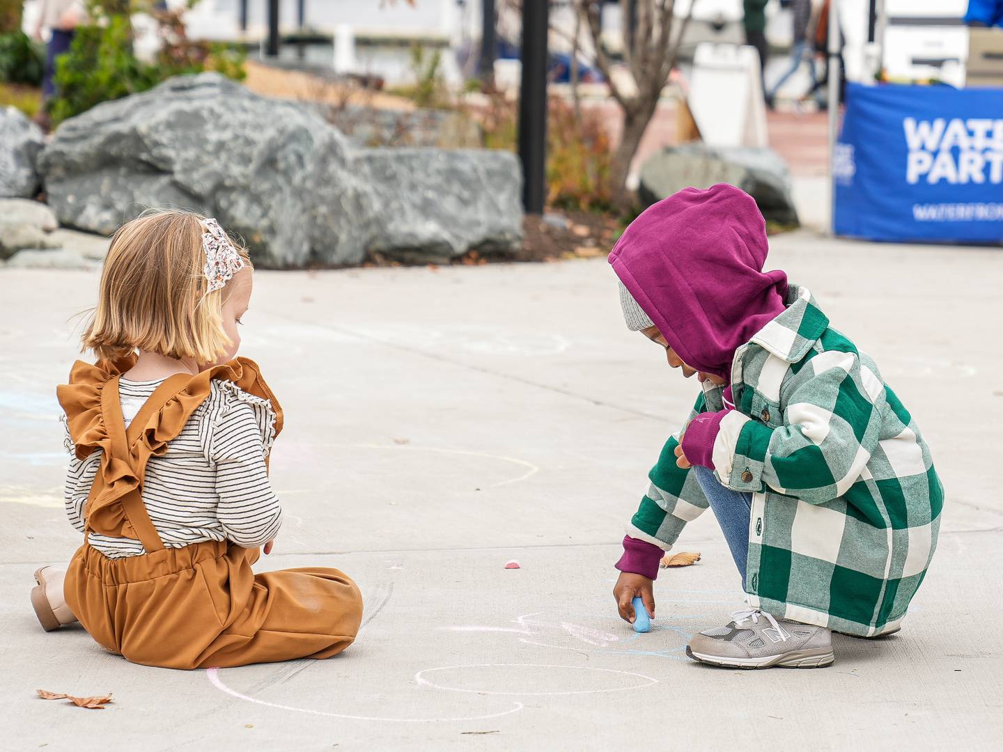 From left, Lottie Cunningham (3.5), and Maddox Carter (3) attempt to keep one another company as they play with the sidewalk chalk, courtesy of the Harbor Harvest Festival.