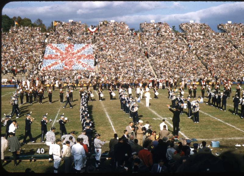 The University of Maryland marching band in formation on the field with the card section forming the Union Jack flag in the background during the Queen's Game at the University of Maryland on October 19, 1957. Courtesy of University of Maryland Archives.
