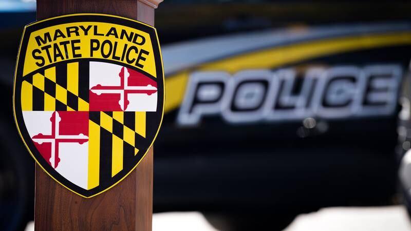 The Maryland State Police logo emblazoned on a lectern in front a police vehicle from a separate agency before a press conference, pictured outside the Maryland State Police Glen Burnie Barracks on 11/10/22.