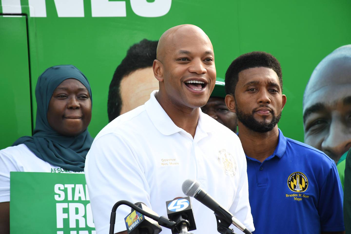 Gov. Wes Moore speaks about the importance of hiring government workers during an event outside the AFSCME union building in southwest Baltimore on Saturday, Sept. 9, 2023. He's joined by Baltimore Mayor Brandon Scott, at right.