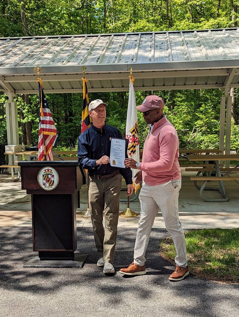 County Executive Steuart Pittman, left, hands Rick Anthony a proclamation Friday, naming the picnic pavilion at Beverly Beach Nature Park in honor of the former recreational and parks director.