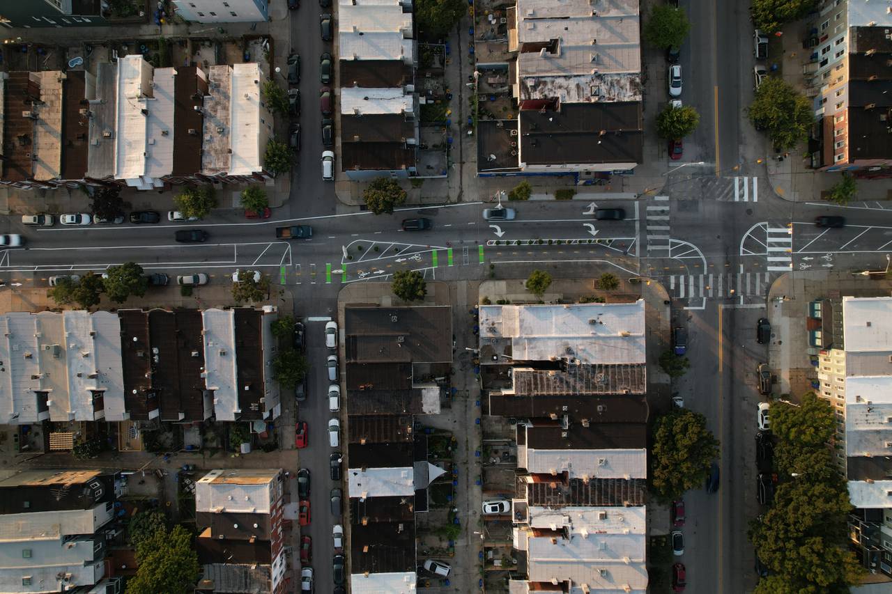 An overhead, bird's eye drone view of multiple city intersections showing a road with a bike lane and a couple of cars.