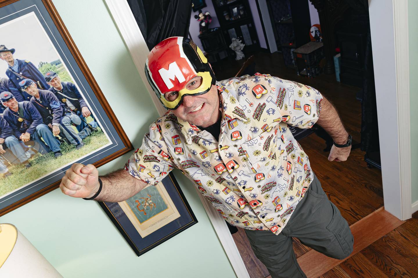 Clark Oliver, also known as Captain Maryland, wears his alter ego’s helmet surrounded by memorabilia from decades of being a costume and sci-fi enthusiast at his home on Wednesday, Dec. 6, 2023. (Wesley Lapointe/for The Baltimore Banner)