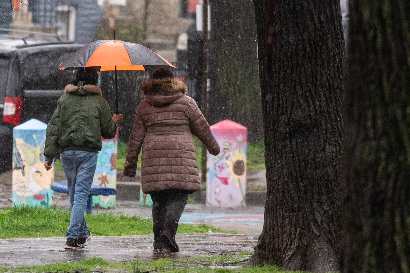 Two people share an umbrella as they walk in the rain.