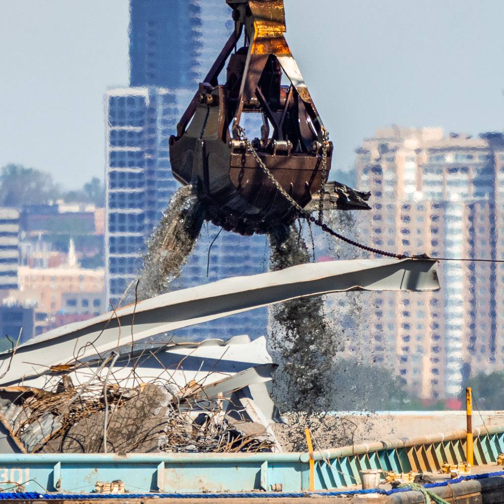 A dredge bucket picks up debris from the Patapsco River and deposits it on a barge on Tuesday, April 16, 2024.